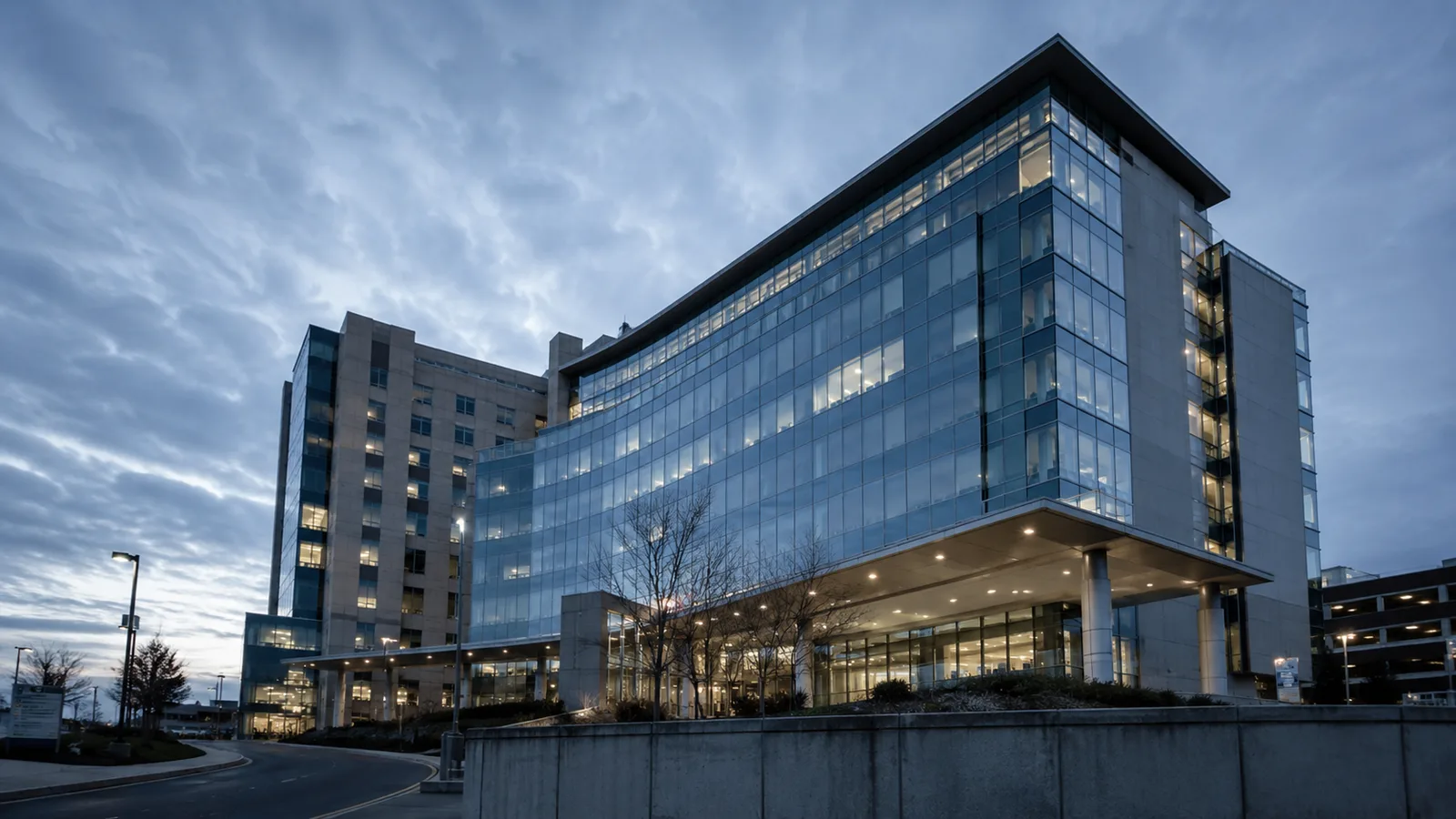 A modern glass hospital building at dusk